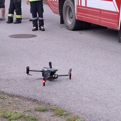 Feuerwehrleute überwachen eine Drohne, die auf der Straße neben einem Einsatzfahrzeug bereitsteht. | © Peter Altphart
