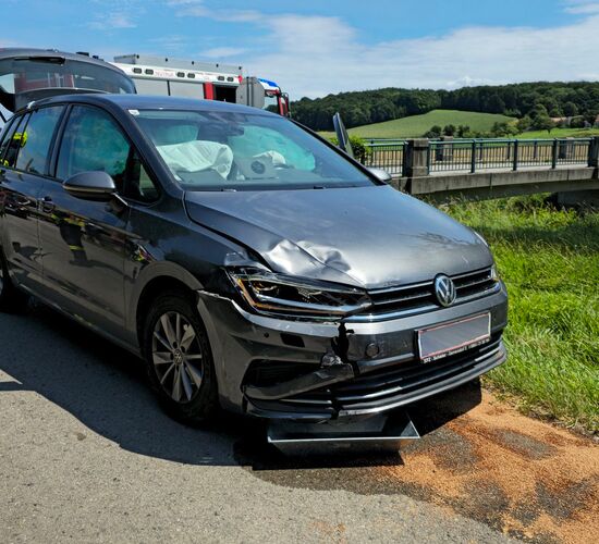 Ein grauer PKW mit Schaden vorne rechts, auslaufender Flüssigkeit und ausgelösten Airbags