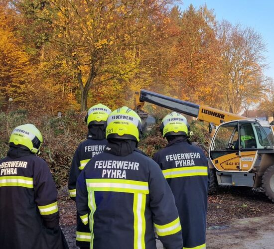 Mit dem Teleskoplader wird der Grünschnitthaufen zerlegt, ein Kamerad kontrolliert mit der Wärmebildkamera