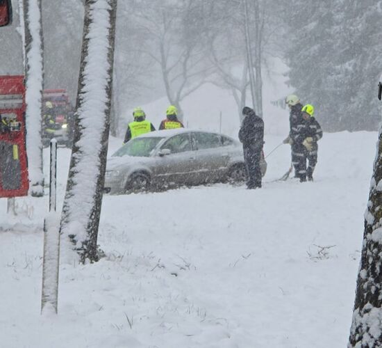 Feuerwehrleute helfen bei starkem Schneefall, ein Auto von der verschneiten Straße zu bergen.