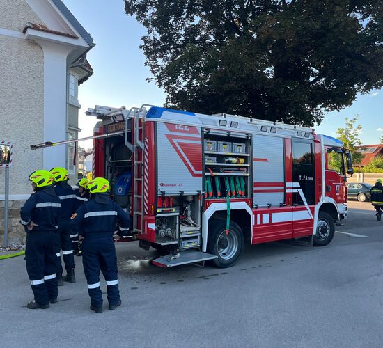 Feuerwehrleute stehen um ein Einsatzfahrzeug, während sie sich auf eine Rettungsaktion vorbereiten. | © Name