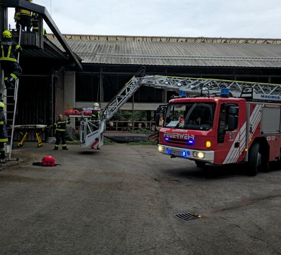 Die Drehleiter bringt den Rettungskorb nach oben, währen gleichzeitig Feuerwehrmänner die Leiter zum Dach hoch klettern