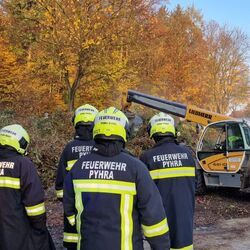 Mit dem Teleskoplader wird der Grünschnitthaufen zerlegt, ein Kamerad kontrolliert mit der Wärmebildkamera