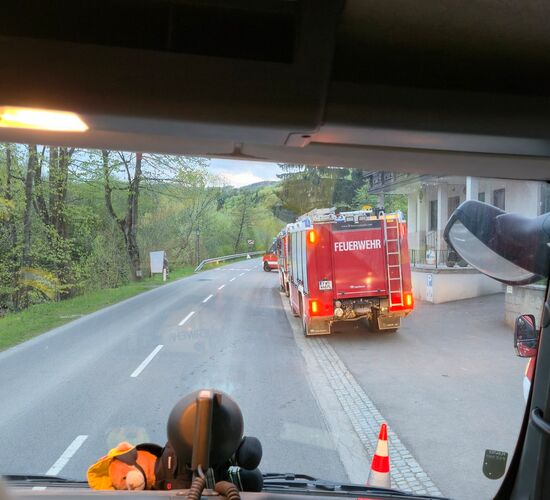 Blick aus dem Feuerwehrfahrzeug auf die Straße, wo mehrere Einsatzfahrzeuge geparkt sind.