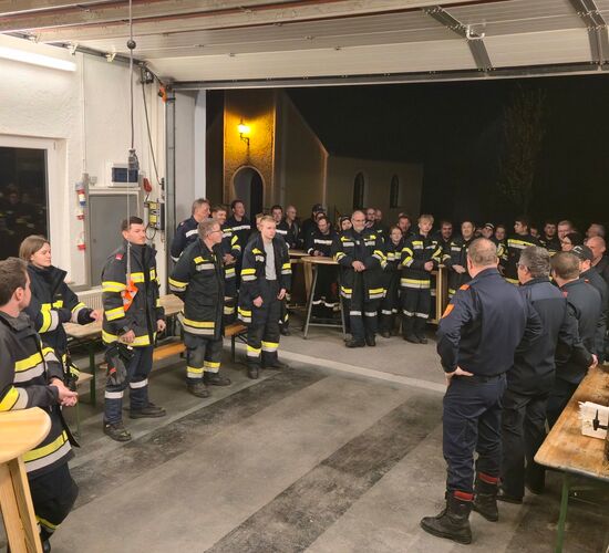 Feuerwehrmitglieder stehen in einer Fahrzeughalle während der Übungs-Nachbesprechung.