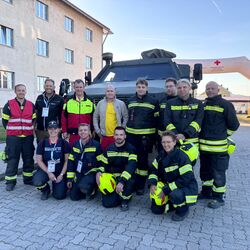 Eine Gruppe von Feuerwehrleuten posiert stolz vor einem Einsatzfahrzeug bei einer Rettungsübung.