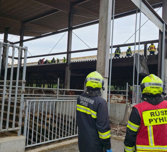 Blick von unten auf das Dach, auf dem die verletzte Person von Rettungsdienst und Feuerwehrleuten Erstversorgt wird