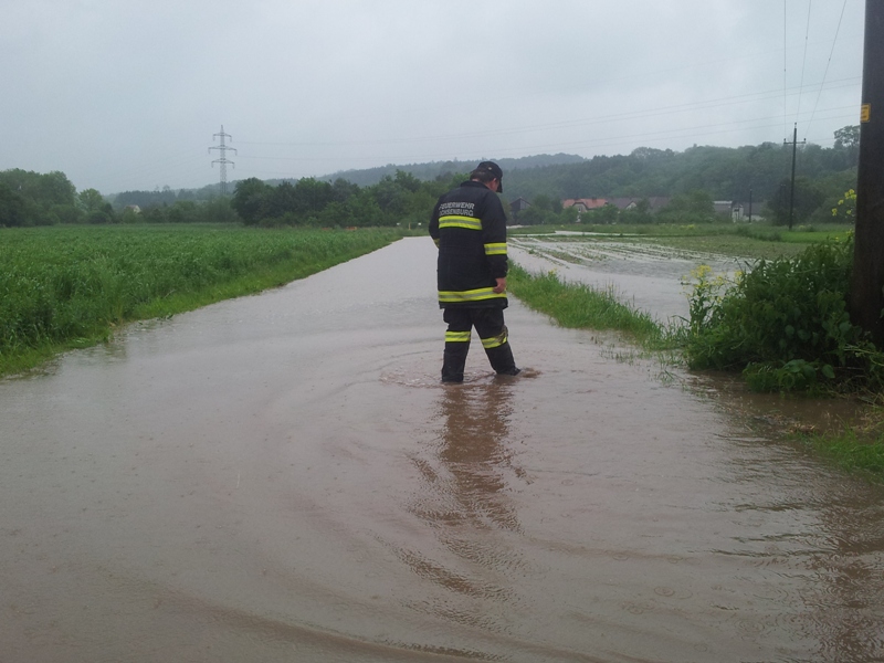 Foto: Feuerwehrmann inspiziert überflutete Straße in Ochsenburg