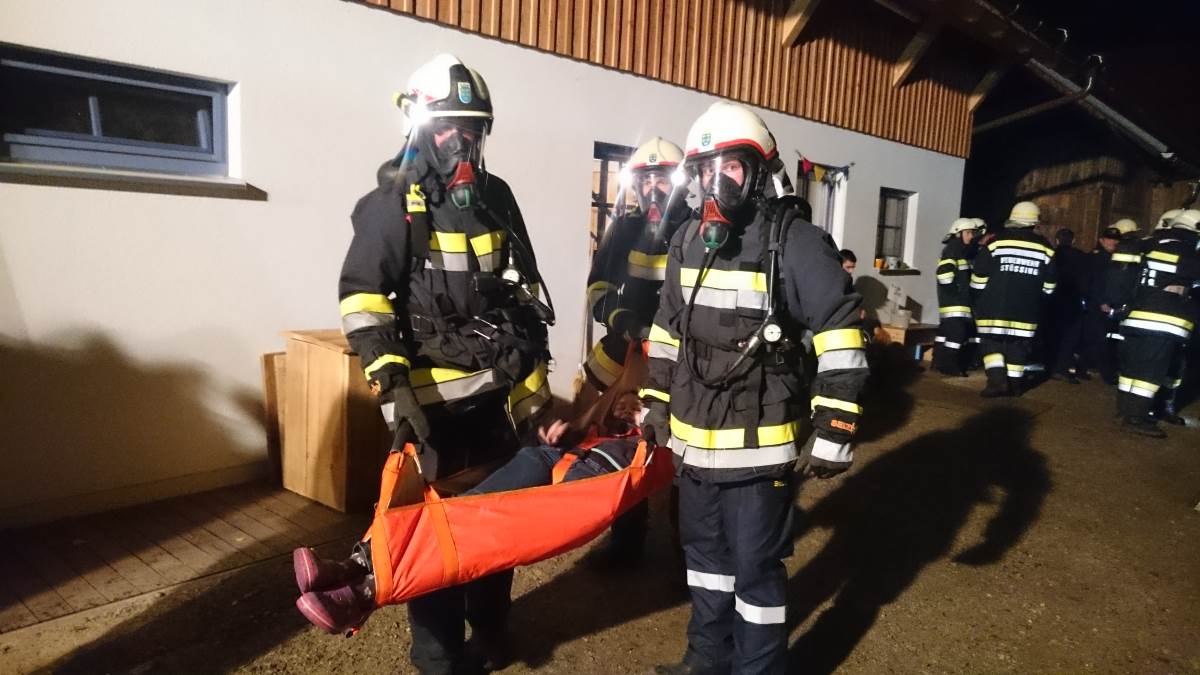 Foto: Ein Atemschutztrupp trägt eine verletzte Person aus dem simulierten Gefahrenbereich