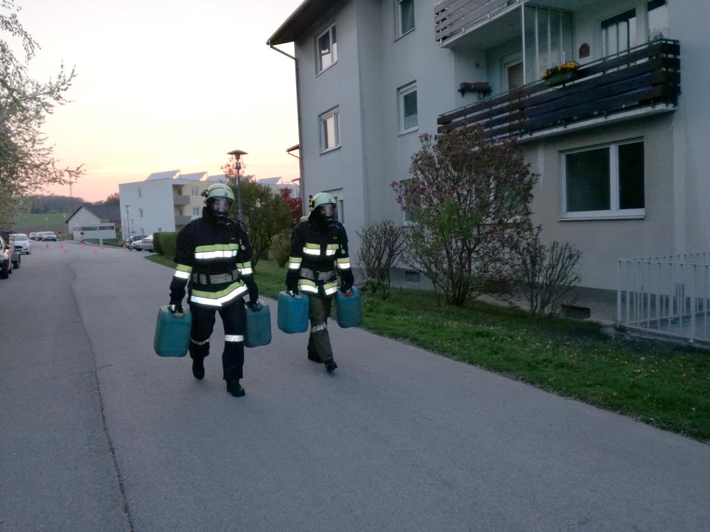 Foto: Zwei voll ausgerüstete Atemschutzgeräteträger gehen mit jeweils zwei gefüllten Wasserkanistern