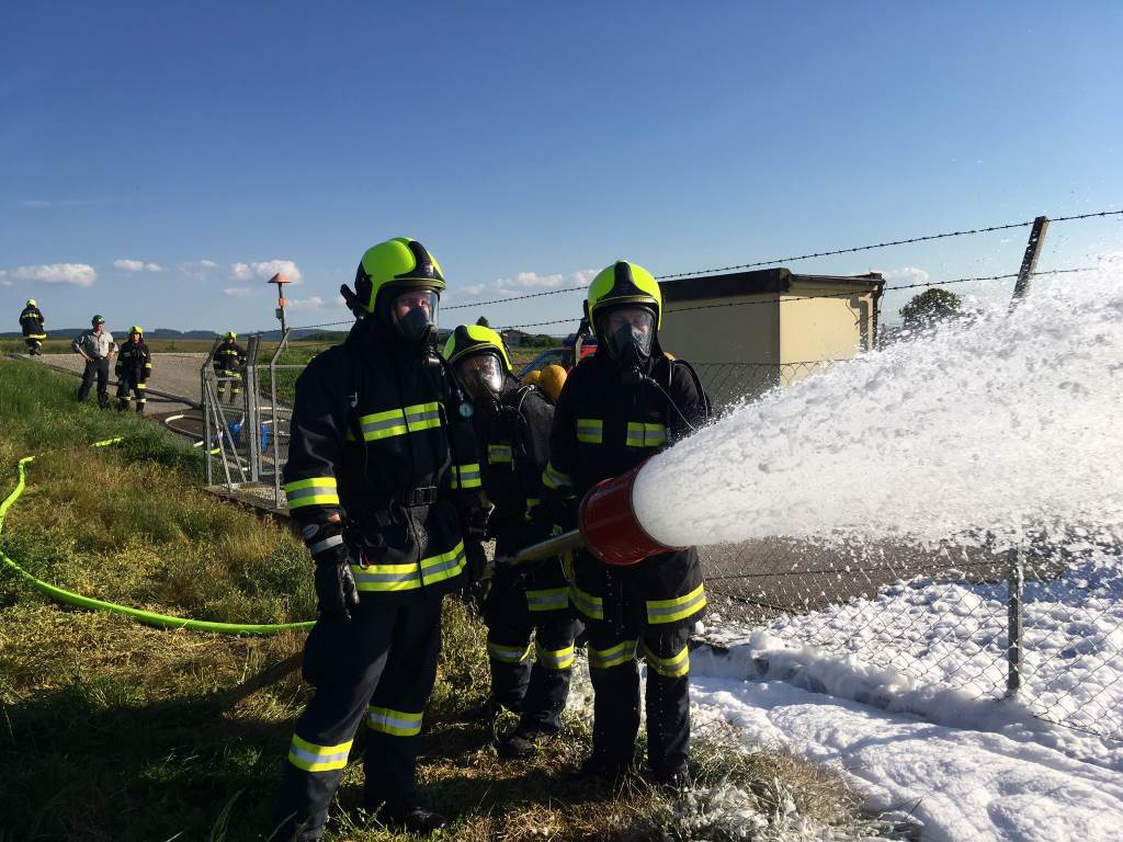 Foto: Zwei Feuerwehrmänner mit Atemschutz und Hitzeschutzausrüstung legen einen Schaumteppich auf