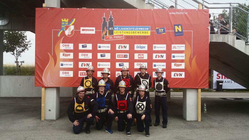 Foto: Die Wettkampftruppe vor einem Plakat des 67. Landesfeuerwehrleistungsbewerbes