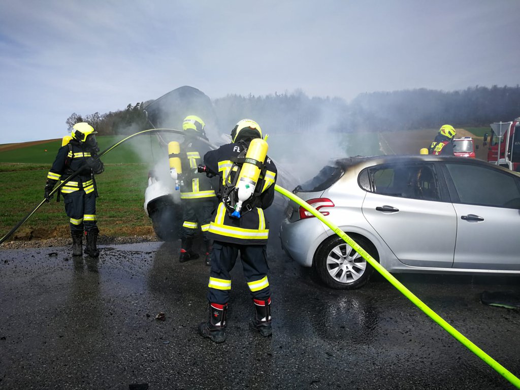 Foto: Die brennenden Autos werden von Feuerwehrleuten mit Atemschutzmasken gelöscht