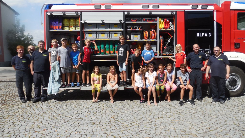 Foto: Die Kinder mit Feuerwehrmännern vor dem Hilfeleistungsfahrzeug (HLFA3)
